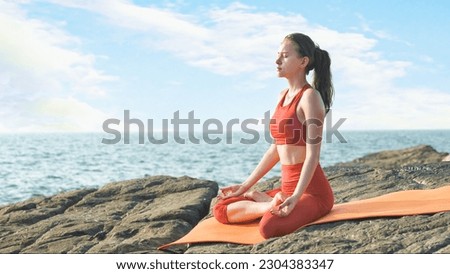 young woman is practicing yoga in a lotus position on the ocean shore