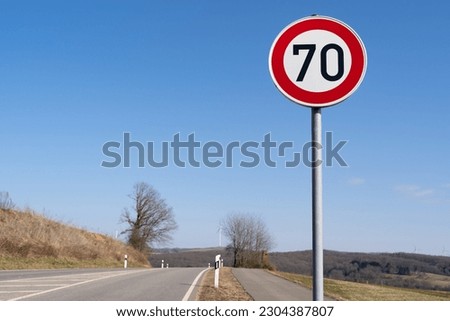 Speed ​​sign 70 kilometers per hour on a country road with blue sunny sky 