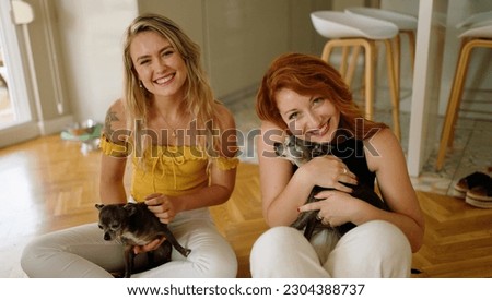Two women smiling confident sitting on floor with chihuahuas at home