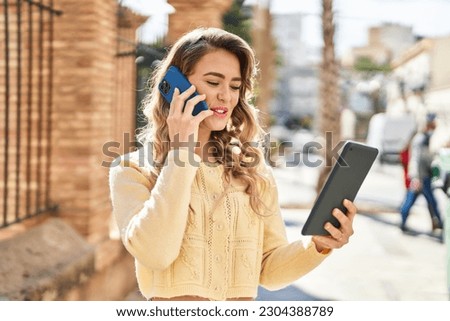 Young woman talking on smartphone using touchpad at street
