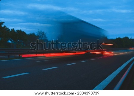 A truck traveling at high speed on the highway. Fast moving freight truck. Motion blur on the highway. Motorway light streams. Concept of international transport, logistics, globalisation and commerce