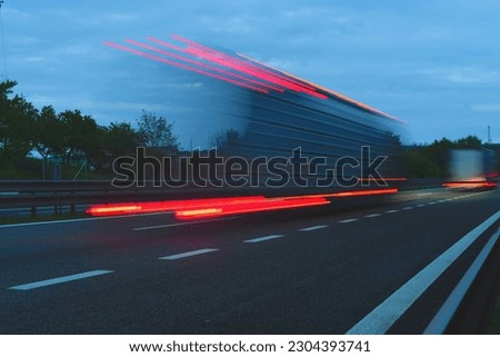 A truck driving on the highway at dusk. Motion blur on the highway. Evening shot of a truck. Fuzzy truck moving at full speed. Concept of international transport, logistics and trade. Global commerce.