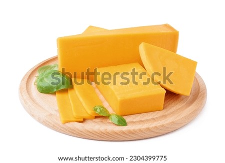 Board with pieces of tasty cheddar cheese and basil on white background Royalty-Free Stock Photo #2304399775