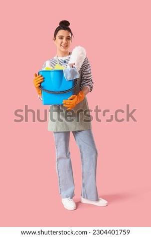 Young woman with cleaning supplies  on pink background