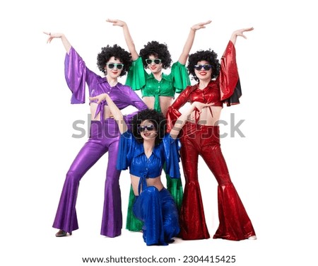 A group of girls in colorful flared suits and afro wigs pose against a white background. Disco style from the eighties or seventies. Royalty-Free Stock Photo #2304415425