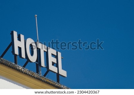 Advertising sign with the inscription hotel in separate letters on the roof against the blue sky