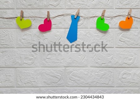 Bright multi-colored garland for Father's Day, birthday, bachelor party, anniversary. Tie and hearts cut out of paper on rope. Preparation for holiday, decoration of house, room, premises. Copy space.