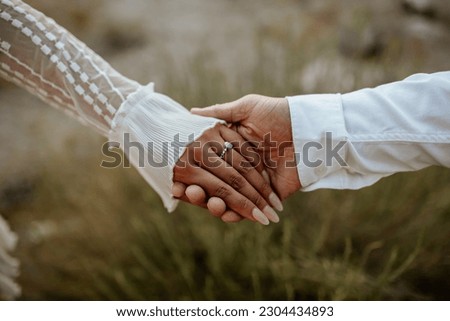 Hands close-up of boho couple in nature holding hands and walking, hugging having fun for their engagement photo session. Royalty-Free Stock Photo #2304434893