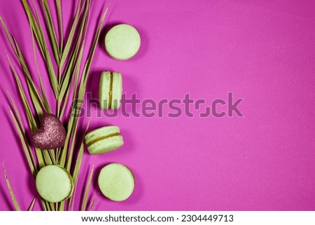 French pistachio macarons and palm leaf and heart glitter on purple background with copy space 