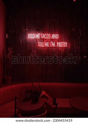 A neon red and pink sign in a Mexican restaurant