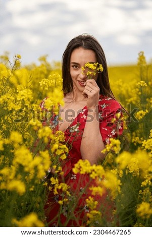 Portrait of a beautiful hispanic young woman in floral dress in a canola field at the end of the spring, in full bloom