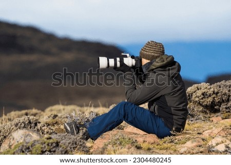 Nature photographer using a telephoto lens in the mountains. Side view