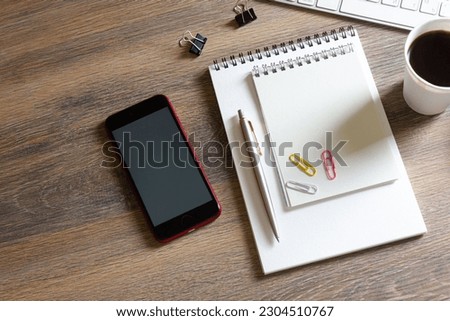 Notebooks, paper clips with a pen and coffee, on a wooden table with a smartphone and a keyboard with a mouse
