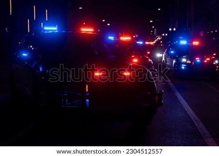 Multiple police cars in the roadway with their lights on Royalty-Free Stock Photo #2304512557