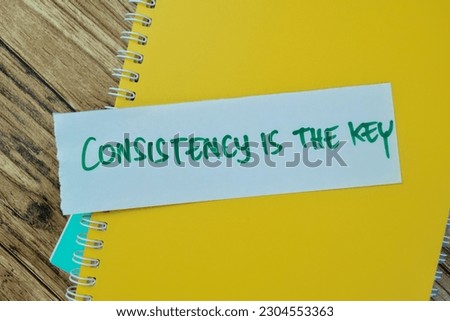 Concept of Consistency is The Key write on sticky notes isolated on Wooden Table.