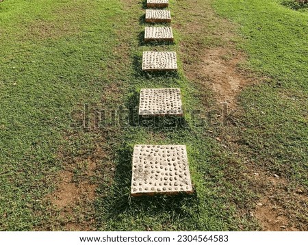 Pathway from Stones and Concrete at the garden outdoor, forward stepping stones or pebbled in the grass lawn