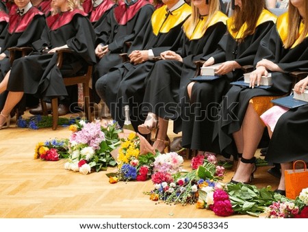 A group of students celebrating graduation, bouquets of flowers presented to graduates