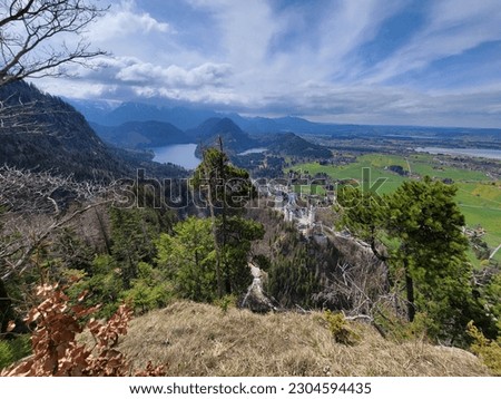 View of Neuschwanstein Castle from an elevated hilltop, with the Bavarian Alps of Southern Germany in the background - Schwangau, Germany