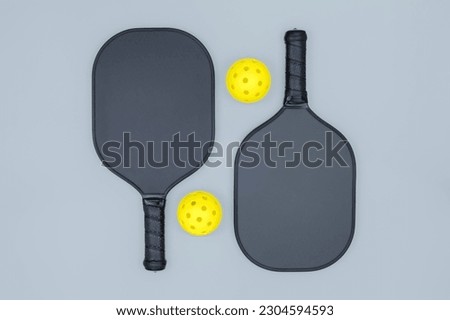 Top view closeup of two pickleball paddles and two yellow balls on light gray background with a copy space Royalty-Free Stock Photo #2304594593