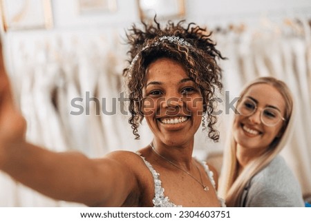 Multiracial happy bride is taking a selfish with her friend
