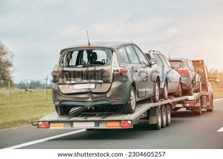 A heavily damaged cars on a trailer is being towed by a tow truck. Royalty-Free Stock Photo #2304605257