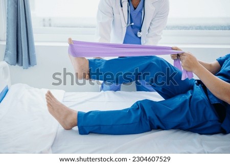 Physiotherapist Helping Patient While Stretching His Leg in bed in clinic or hospital 
