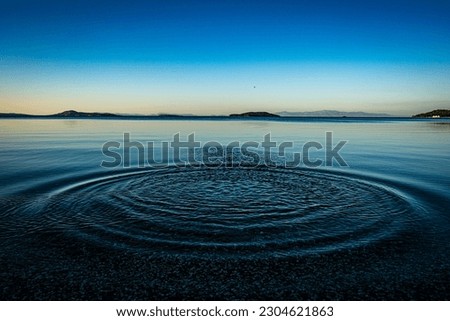 Round droplets of water over circles on the pool water. Water drop, whirl and splash. Ripples on sea texture pattern background. Desktop  laptop wallpaper. Closeup water rings affect the surface. Royalty-Free Stock Photo #2304621863