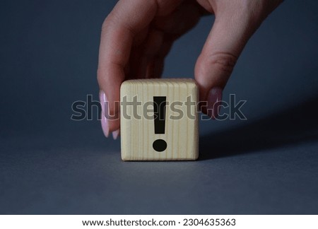 Exclamation mark symbol. Exclamation mark on wooden cubes. Businessman hand. Beautiful grey background. Business and Exclamation mark concept. Copy space.