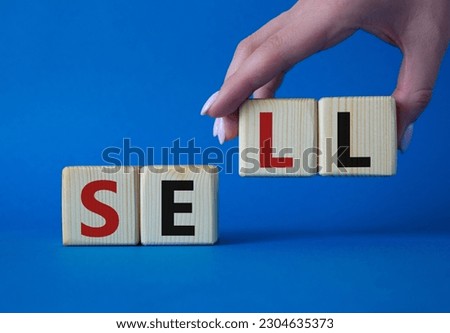 Sell symbol. Concept word Sell on wooden cubes. Businessman hand. Beautiful blue background. Business and Sell concept. Copy space.