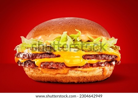 double smash burger with cheesy cheddar, onion and lettuce on a brioche bun on a red background Royalty-Free Stock Photo #2304642949