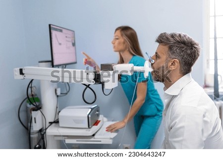Man performing pulmonary function test and spirometry using spirometer at medical clinic. Spirometry of lungs Royalty-Free Stock Photo #2304643247