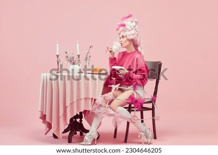 Royalty breakfast. Portrait of elegant princess, queen wearing pink clothes, and wig drinking coffee over pink background. Concept of comparison of eras, modernity and renaissance, beauty, history Royalty-Free Stock Photo #2304646205