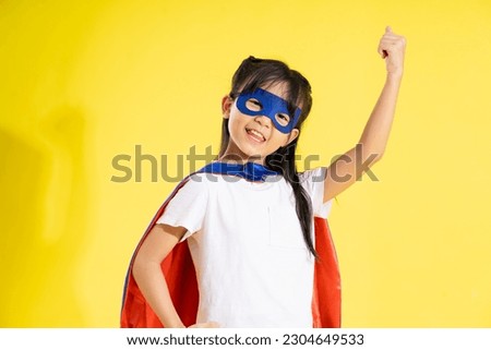 Portrait of little girl dressed up as a hero, isolated on yellow