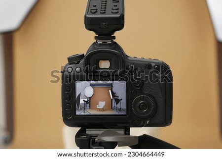 Camera on tripod, armchair and professional lighting equipment in modern photo studio, closeup