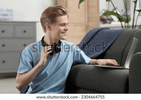 Online learning. Smiling teenage boy near laptop at home