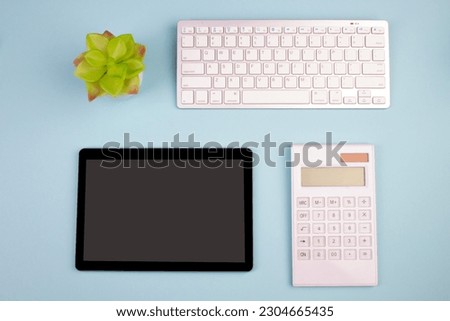 Tablet, calculator, phone, pen and a cup of coffee, lot of things on a blue background. Top view with copy space
