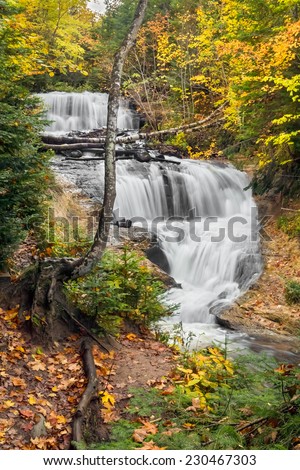 Sable Falls, a beautiful cascading waterfall in Michigan's Pictured Rocks National Lakeshore, flows through a colorful autumn landscape.