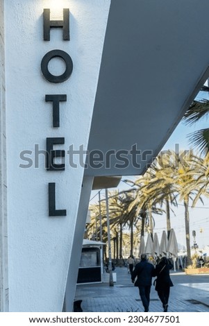 Sign on the facade of a hotel in a Mediterranean village, background out of focus.