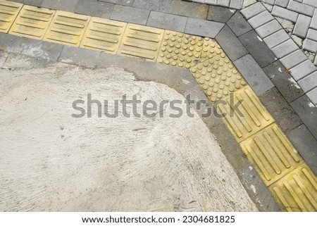 Yellow blocks of tactile paving for blind handicap. Guiding Braille blocks, tactile tiles for the visually impaired, Tenji blocks. Textured ground surface indicators located on sidewalks, stairs.
