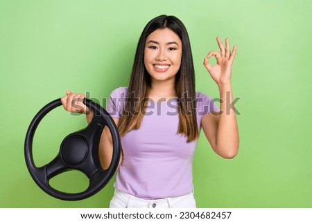 Photo of chinese young attractive woman okey sign advertisement new driving auto school hold steering wheel isolated on green background