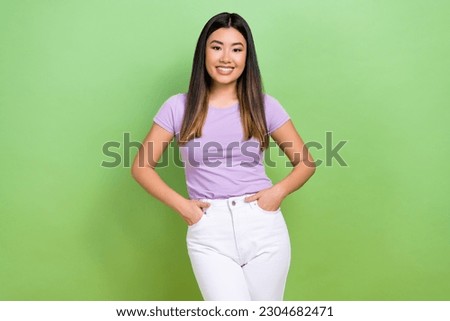 Photo portrait of pretty  chinese young girl hand pockets posing dressed stylish violet outfit isolated on green color background