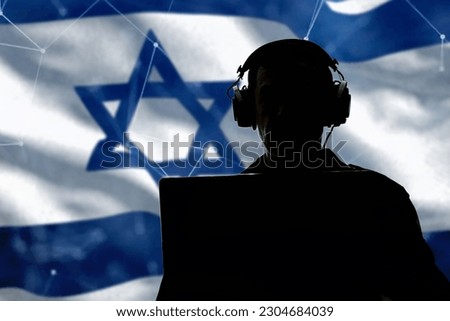 Silhouette of a military man in headphones at a laptop against the background of the flag of Israel, contour lighting. Concept: collection of confidential information, Jewish special services.