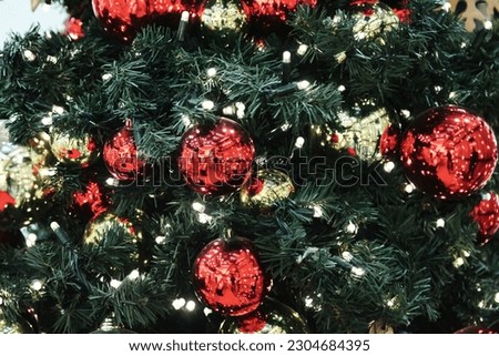 Christmas festive decorations on holiday Christmas tree. Many colorful red balls garland glowing lamps on branches fir. Festive traditional seamless background for New Year. Copy text space