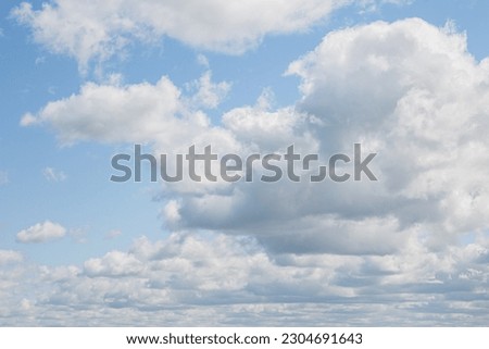 White fluffy clouds on a summer blue sky in cartoon style for background or wallpaper design. White of round clouds in a blue sky.