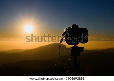 Silhouette of professional camera on top of mountains during sunrise