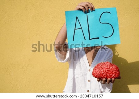 unrecognizable woman holding a als acronym card and a red brain Royalty-Free Stock Photo #2304710157