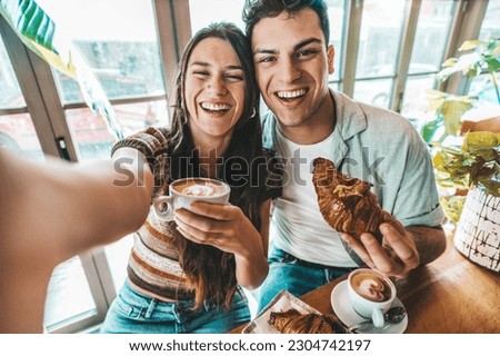 Happy couple enjoying breakfast drinking coffee at bar cafeteria - Life style concept with guy and girl in love having date moment sitting at restaurant in the city centre Royalty-Free Stock Photo #2304742197