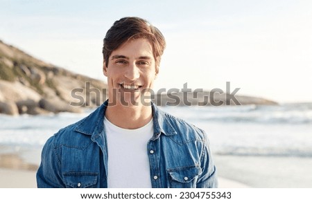 Man, portrait and beach with sunshine and smile in the outdoors for an adventure and happiness. Ocean, sun and male person is happy in the outdoor for day to relax in the summer with nature and air.
