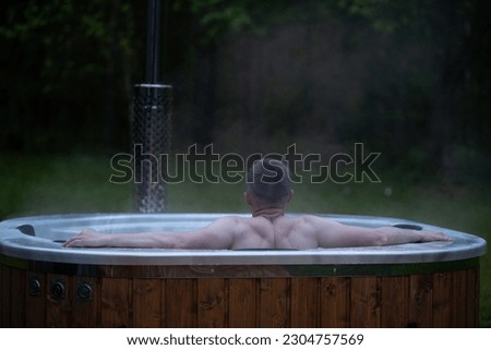 Man relax in outside hot tub SPA surrounded by trees and forest. High quality photo