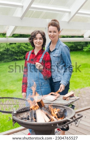 Barbeque party in garden with mom and her daughter at the grill in a country house